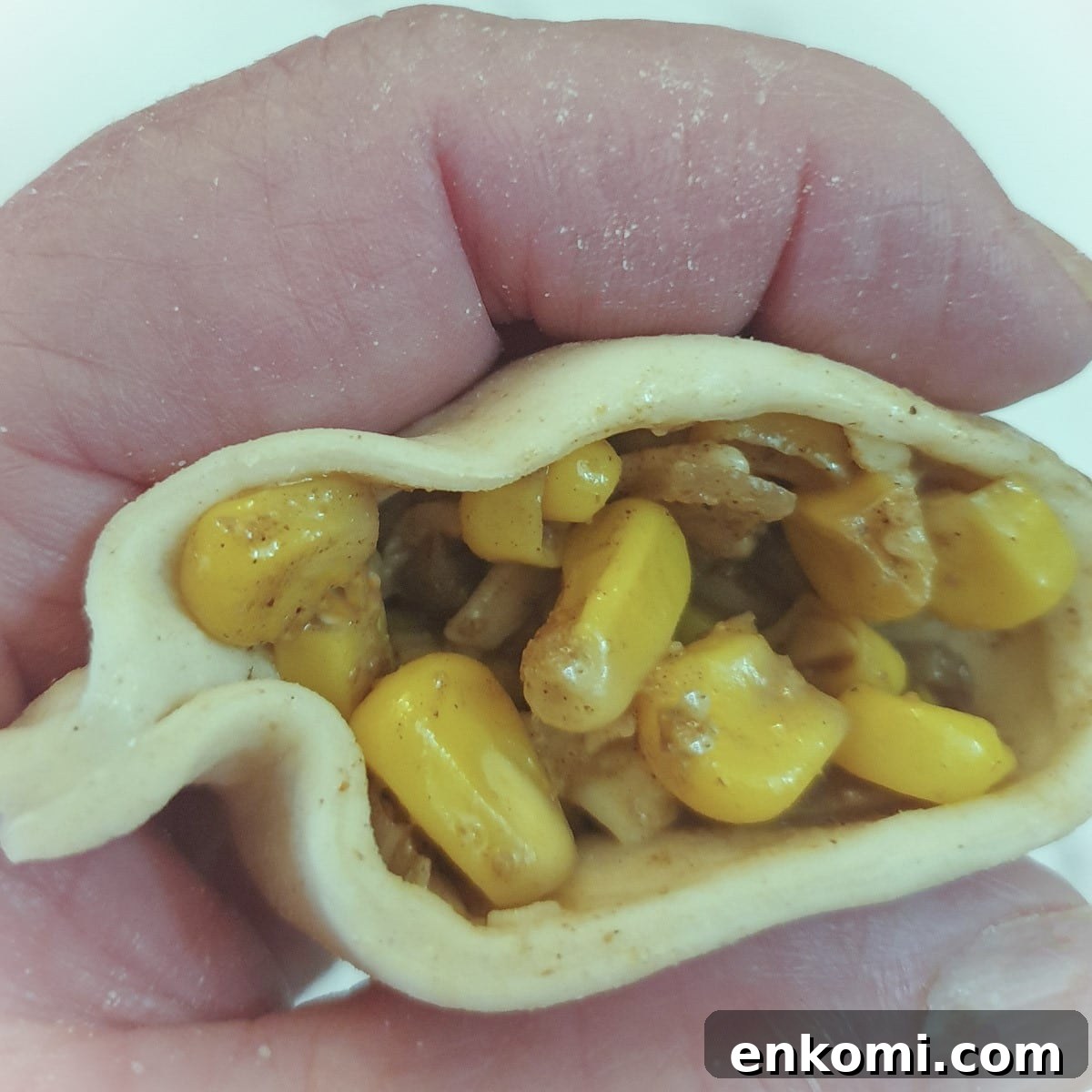 Cheese and sweetcorn filling being spooned into a pastry shell.