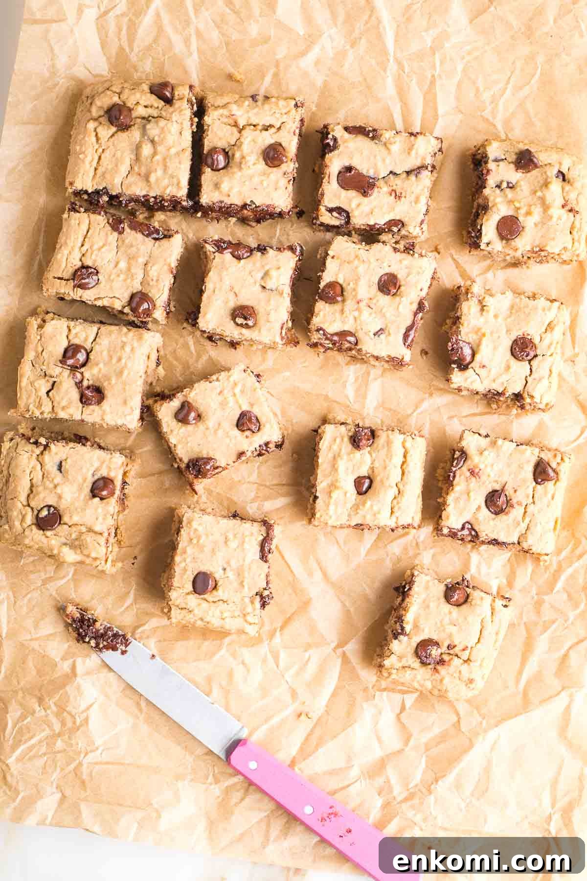 White bean blondies with chocolate chips, cut into squares with a pink knife. 