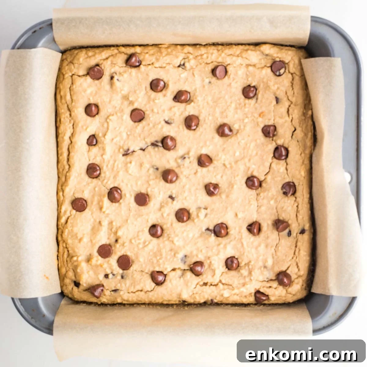 Baked blondies with chocolate chips in a square baking pan with parchment paper.