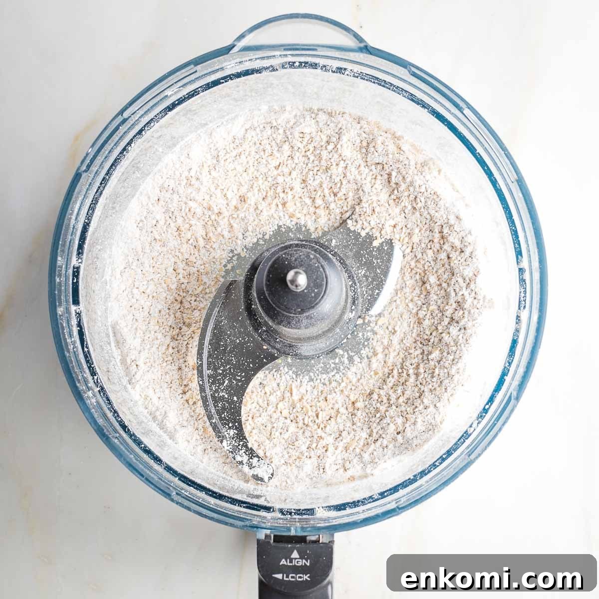 Rolled oats ground into oat flour in the bowl of a food processor. 