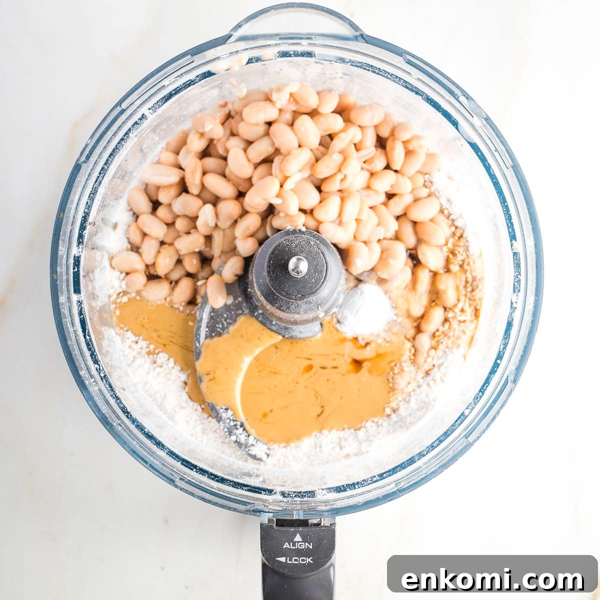 Food processor bowl withwhite beans, flour, tahini, baking powder and syrup.