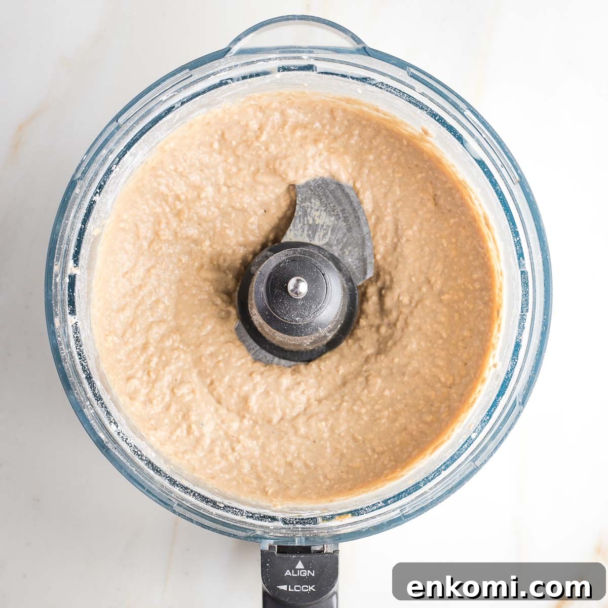 Light colored cookie batter in the bowl of a food processor. 