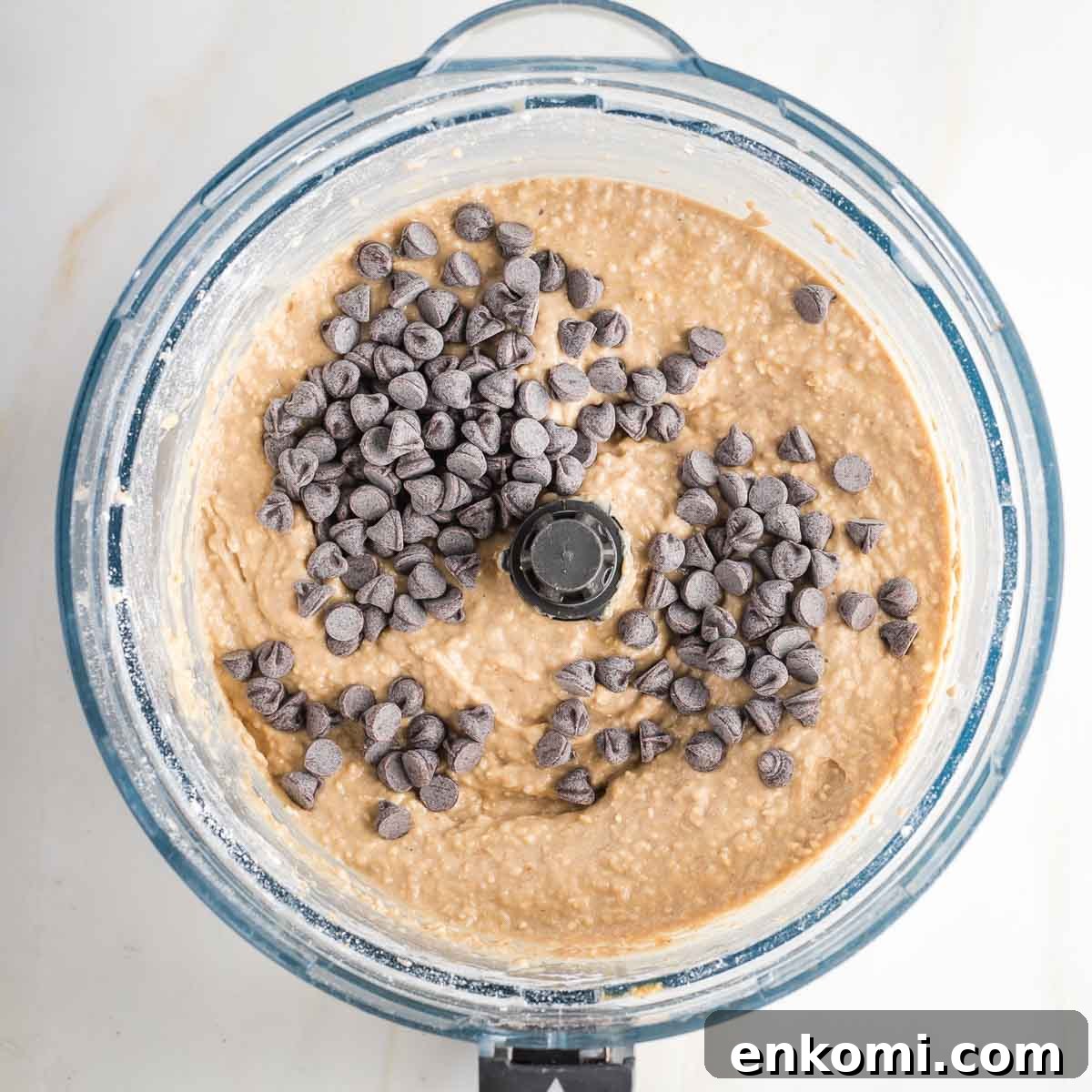Blondie batter in food processor bowl with chocolate chips on top.