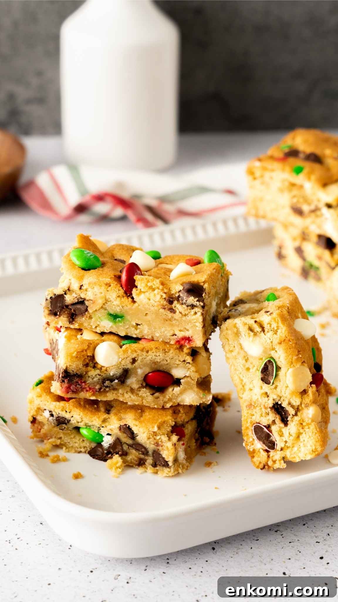 Christmas Sugar Cookie Bars stacked on a white plate with a glass of milk in the background.
