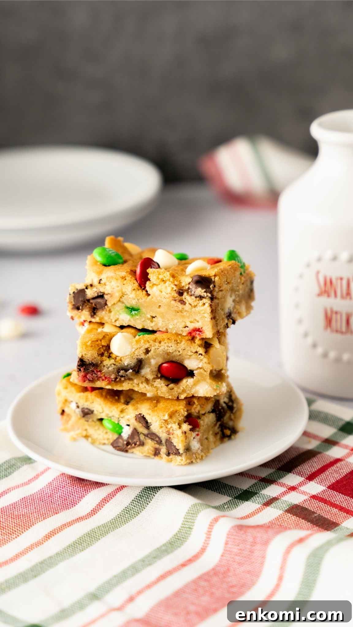 Three Christmas Sugar Cookie Bars stacked on a white plate next to a jug of milk.