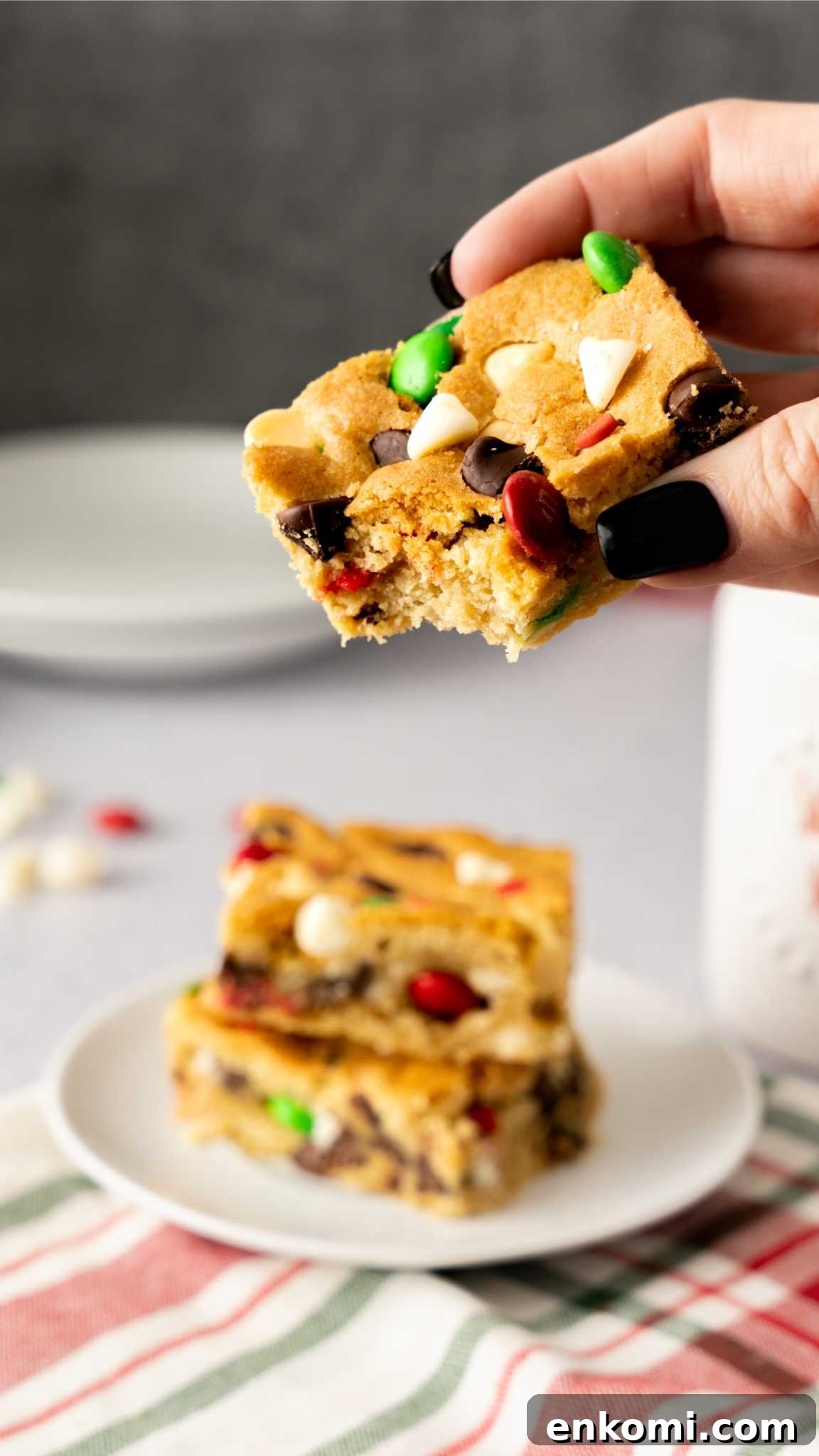 A bite out of a Christmas Sugar Cookie Bar being held by a manicured hand.
