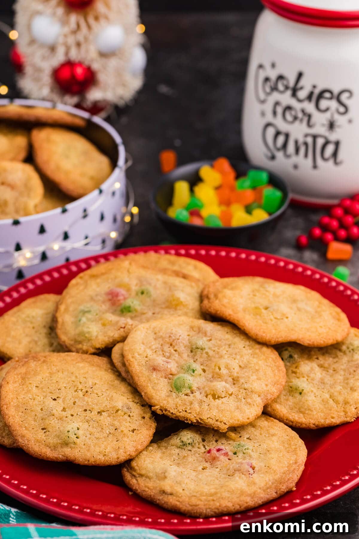 Gumdrop Cookie Recipe: Soft, Chewy Holiday Treats 2 Gumdrop cookies on a red plate, studded with colorful candy pieces, surrounded by festive Christmas decor and a “Cookies for Santa” jar.