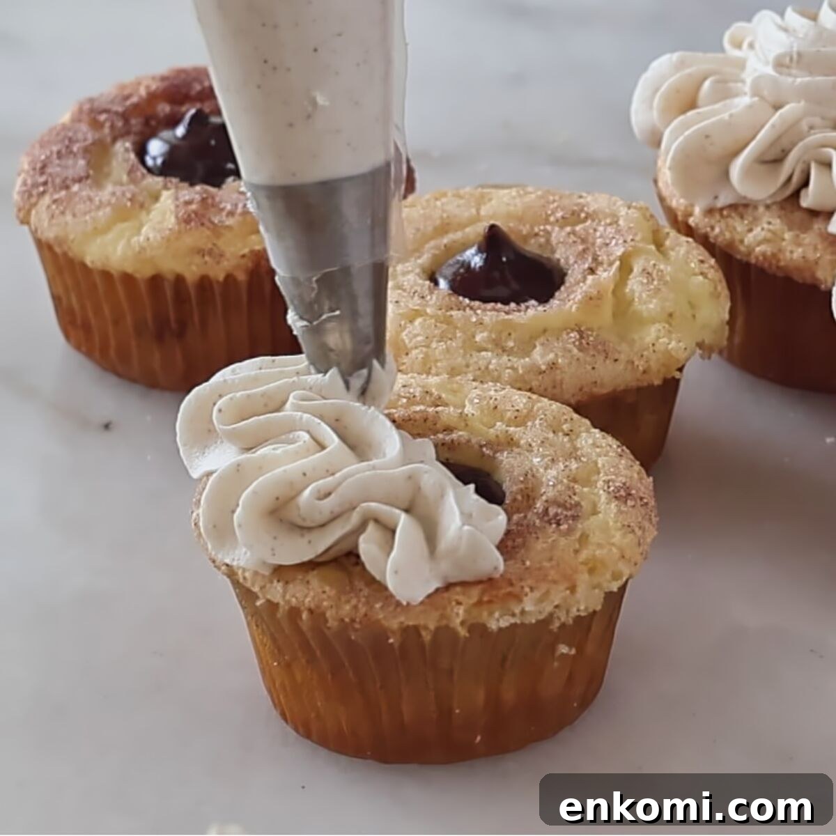Gluten-Free Churro Cupcakes Recipe with Cinnamon Sugar Topping 19 piping frosting on top of filled cupcakes.
