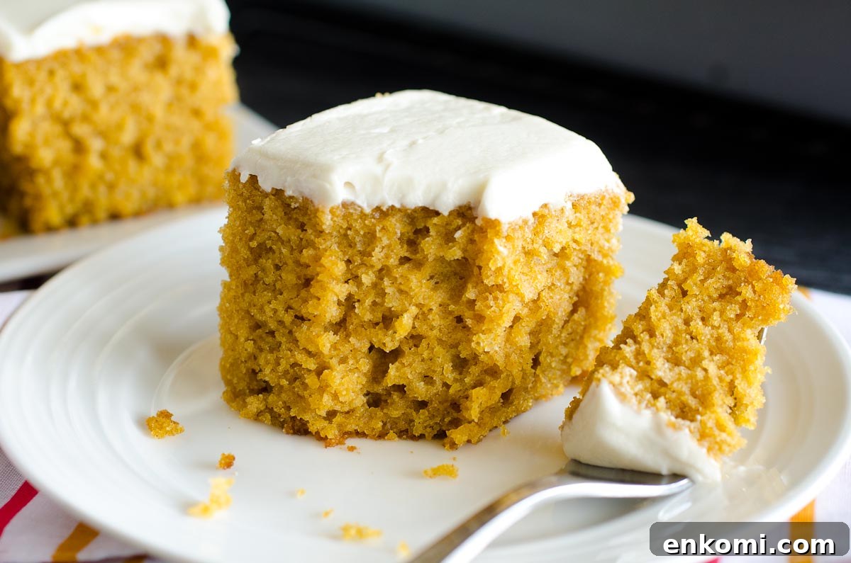 bite out of pumpkin bar with cream cheese frosting on round plate with fork