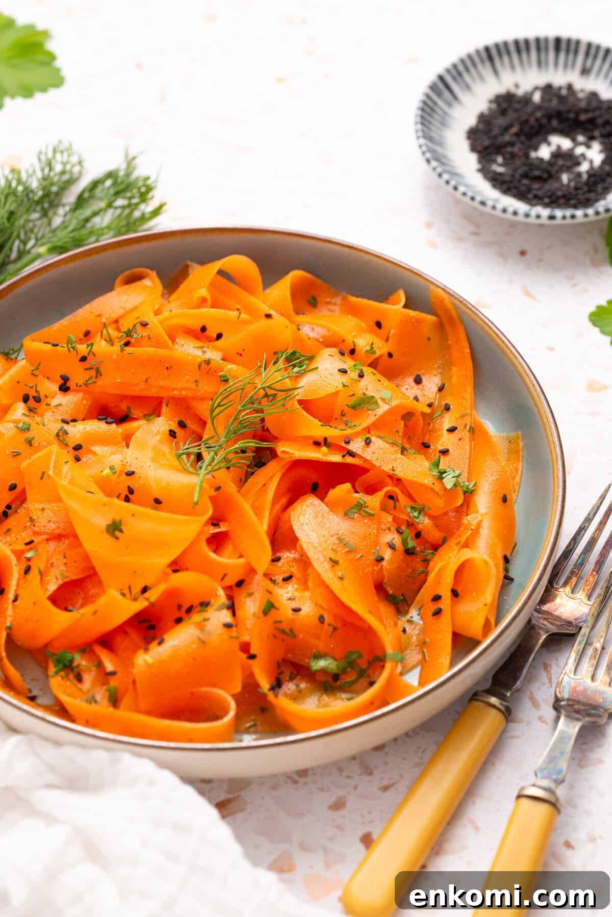 An image of raw carrot salad on a serving plate with two forks on the side.