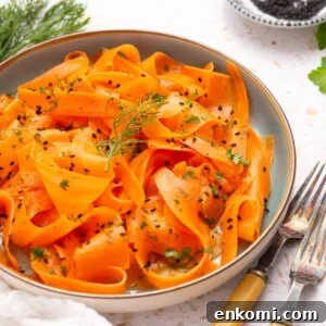 An image of raw carrot salad on a serving plate with two forks on the side.