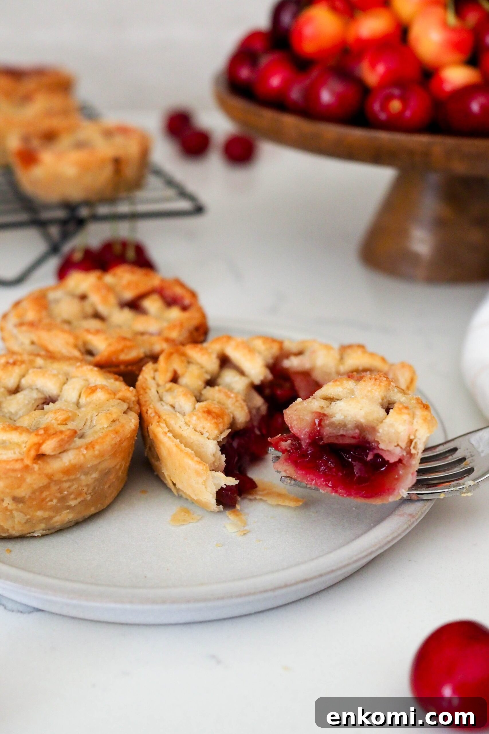 Mini Cherry Pies Recipe: Perfect Handheld Fruit Tarts 2 A fork pulls a piece of mini cherry pie off a plate.