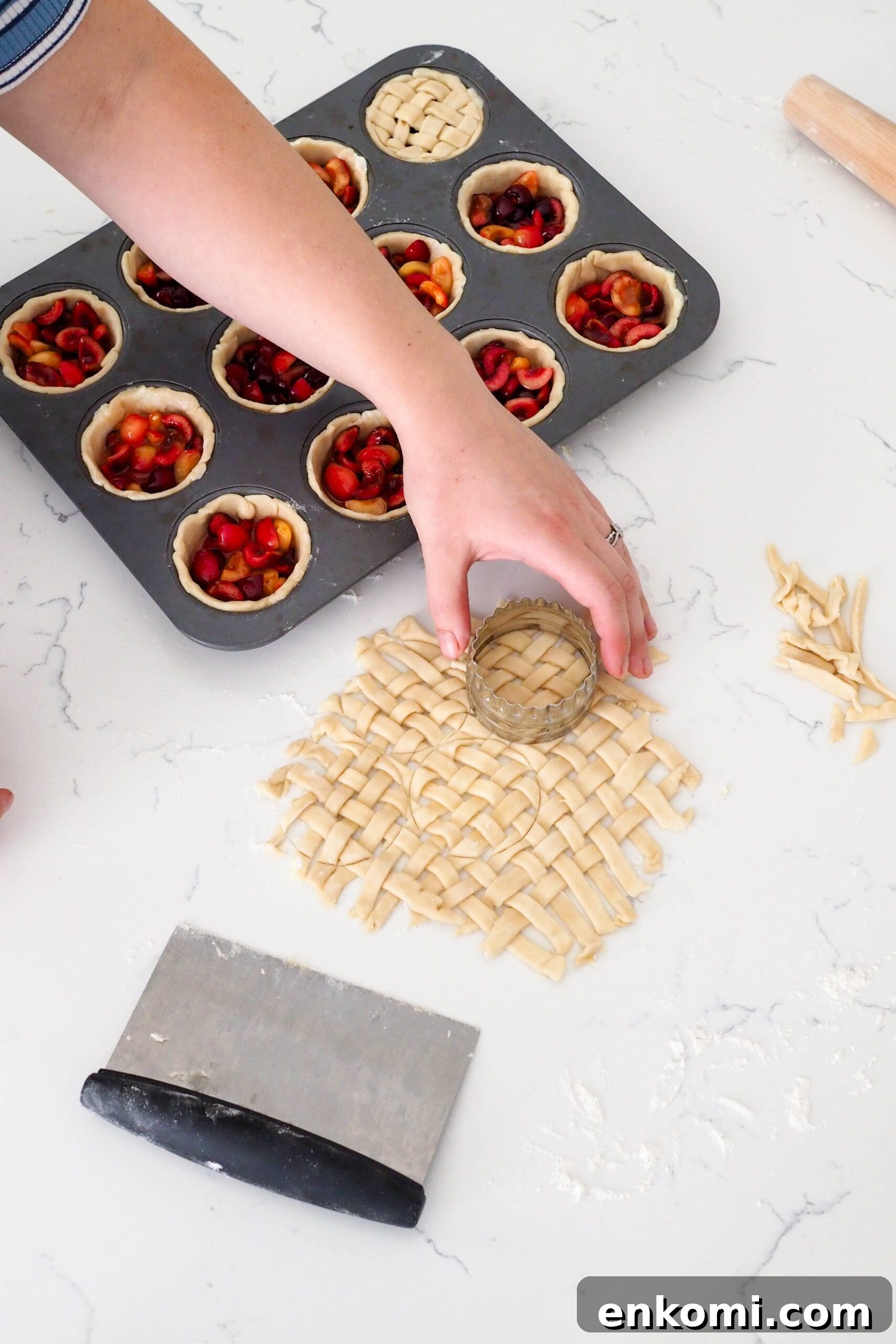 Mini Cherry Pies Recipe: Perfect Handheld Fruit Tarts 10 A hand uses a round cutter to cut out a small lattice.