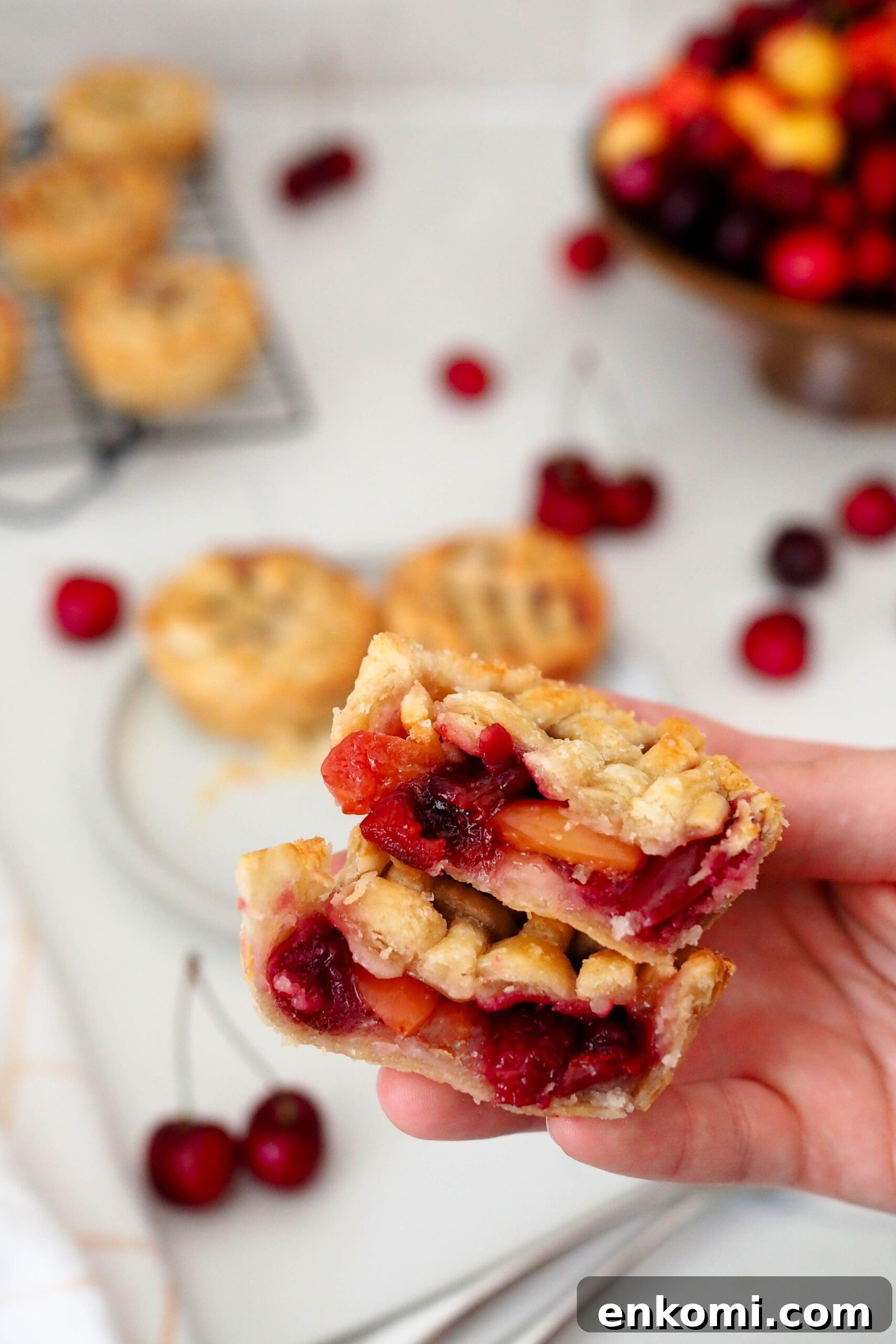 Mini Cherry Pies Recipe: Perfect Handheld Fruit Tarts 14 A hand holds up two halves of a mini cherry pie.
