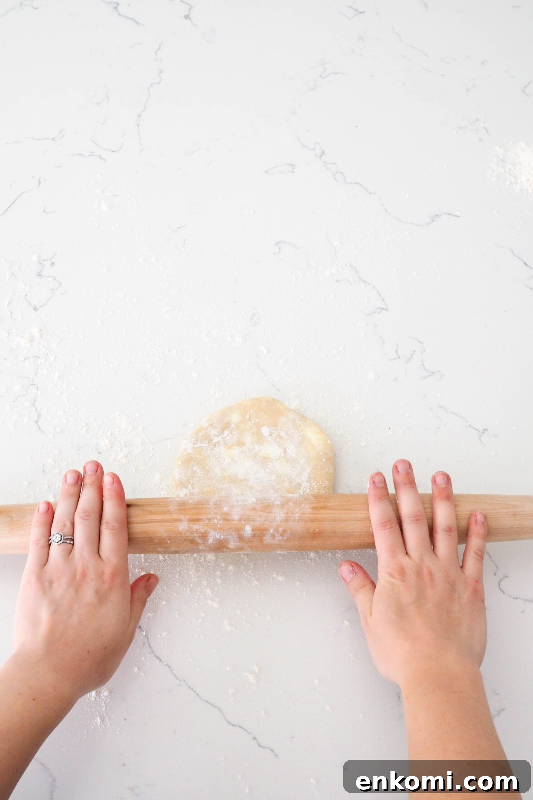 Mini Cherry Pies Recipe: Perfect Handheld Fruit Tarts 6 Two hands push a rolling pin over a pie crust.