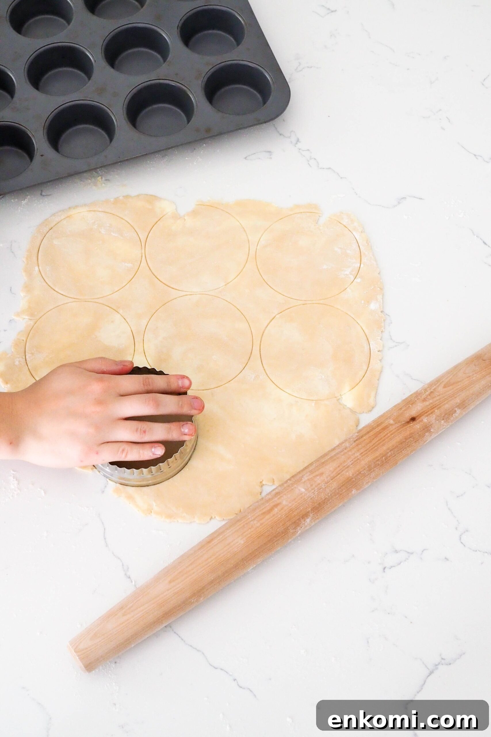Mini Cherry Pies Recipe: Perfect Handheld Fruit Tarts 7 A hand cuts circles out of a rolled out pie crust.