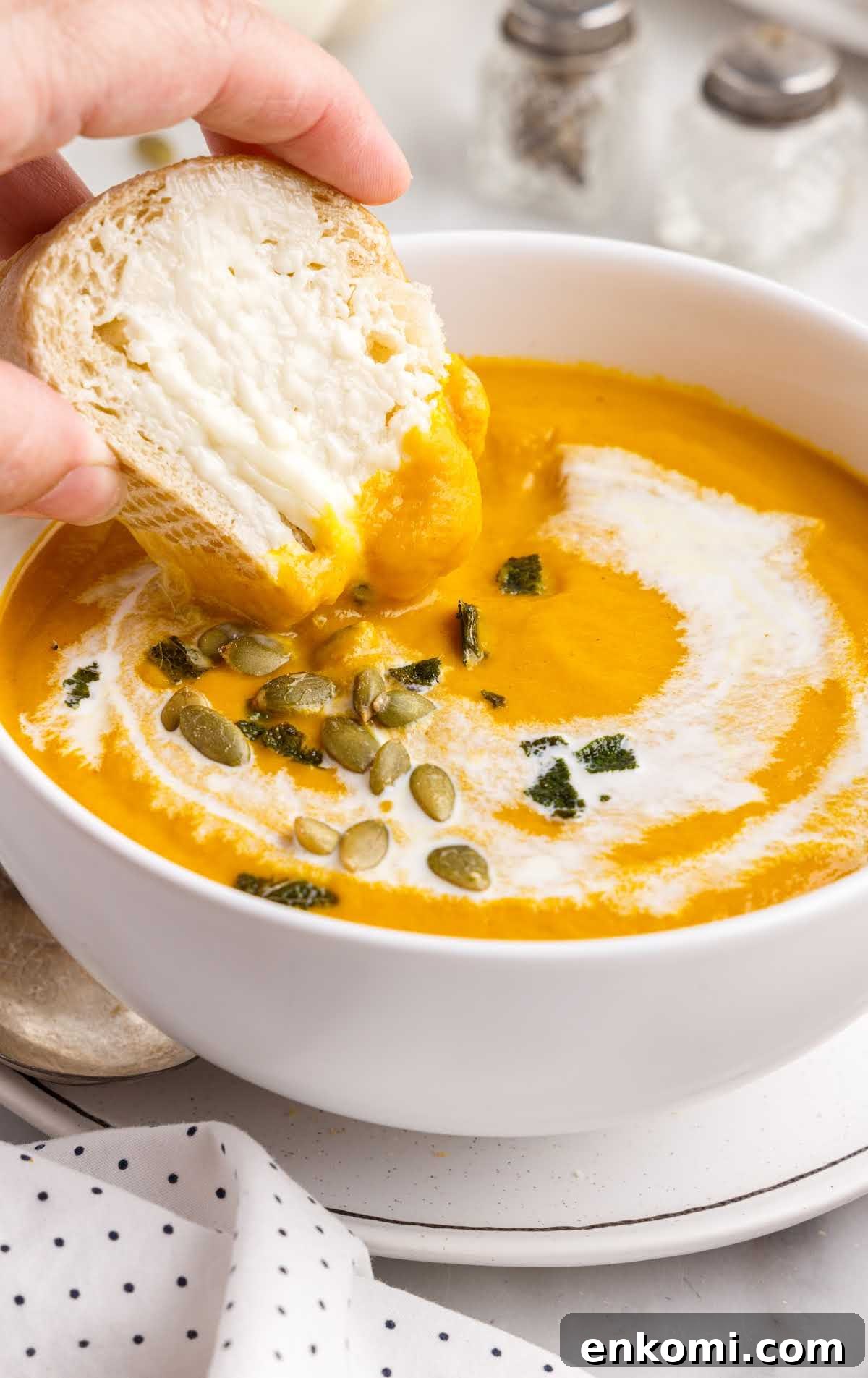 close up shot of Pumpkin Soup in a bowl with bread being dipped in it