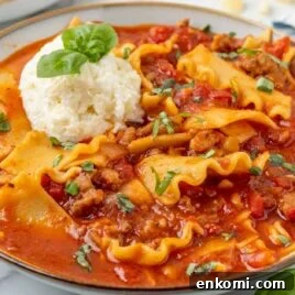 close up shot of a bowl of Lasagna Soup topped with parmesan cheese and garnished with basil