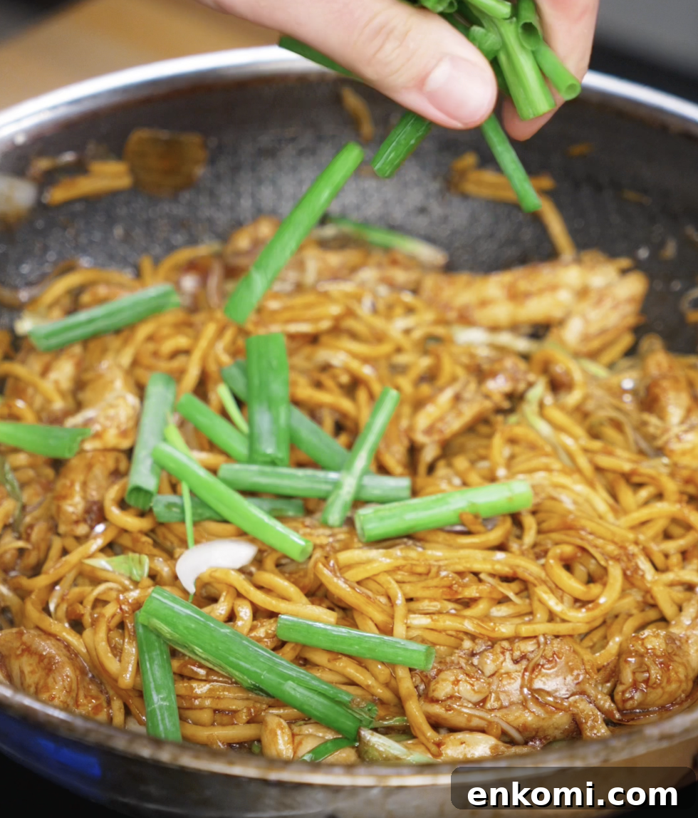 Crispy Chicken Pan-Fried Noodles with Garlic Scallions 10 Fresh scallion greens are being added to the pan as the final touch. They add a pop of color, crunch, and brightness to the finished noodles.