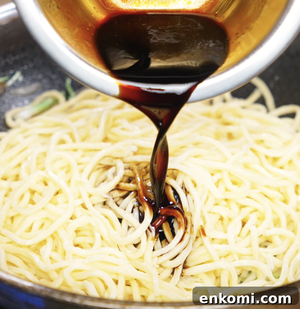 Crispy Chicken Pan-Fried Noodles with Garlic Scallions 9 A rich, dark soy-based sauce is being poured over just-cooked noodles in the wok. The sauce will coat the noodles and tie all the flavors together.