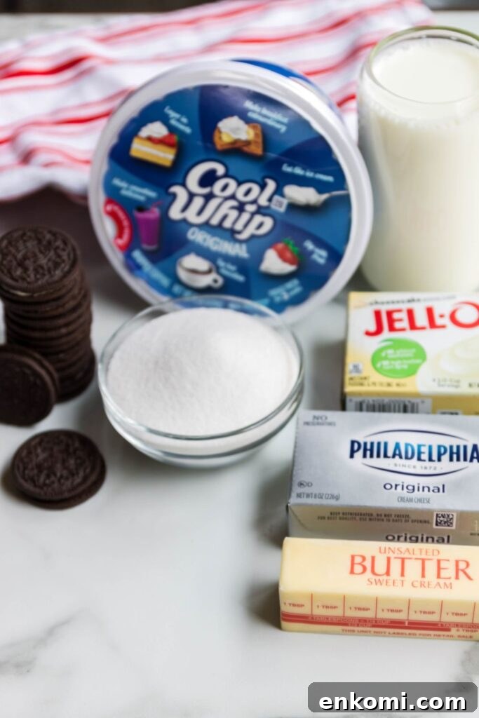 Oreo dessert ingredients on counter, milk, jello, butter, cream cheese, Oreo cookies and tub of cool whip 