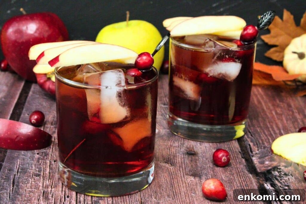 two crownberry apple drinks with fresh apple slices and cranberries