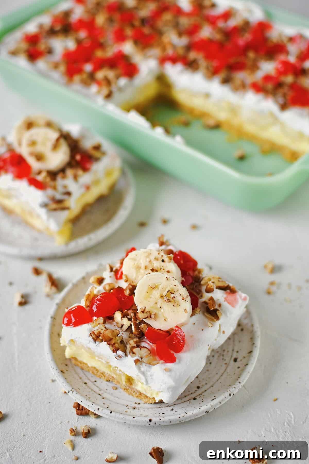 Decadent Banana Split Layer Cake Recipe 2 Banana Split Cake in the baking dish, a couple of slices removed and ready to eat that have been topped with banana slices just before serving.