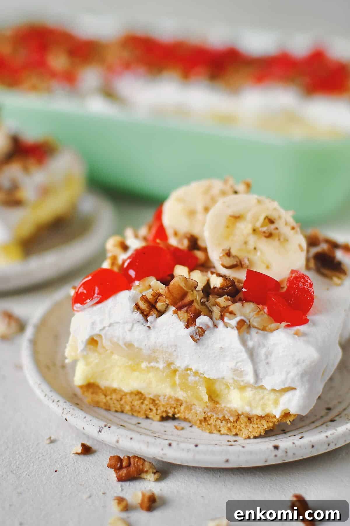 Decadent Banana Split Layer Cake Recipe 11 Banana Split Cake in the baking dish, a couple of slices removed and ready to eat that have been topped with banana slices just before serving.