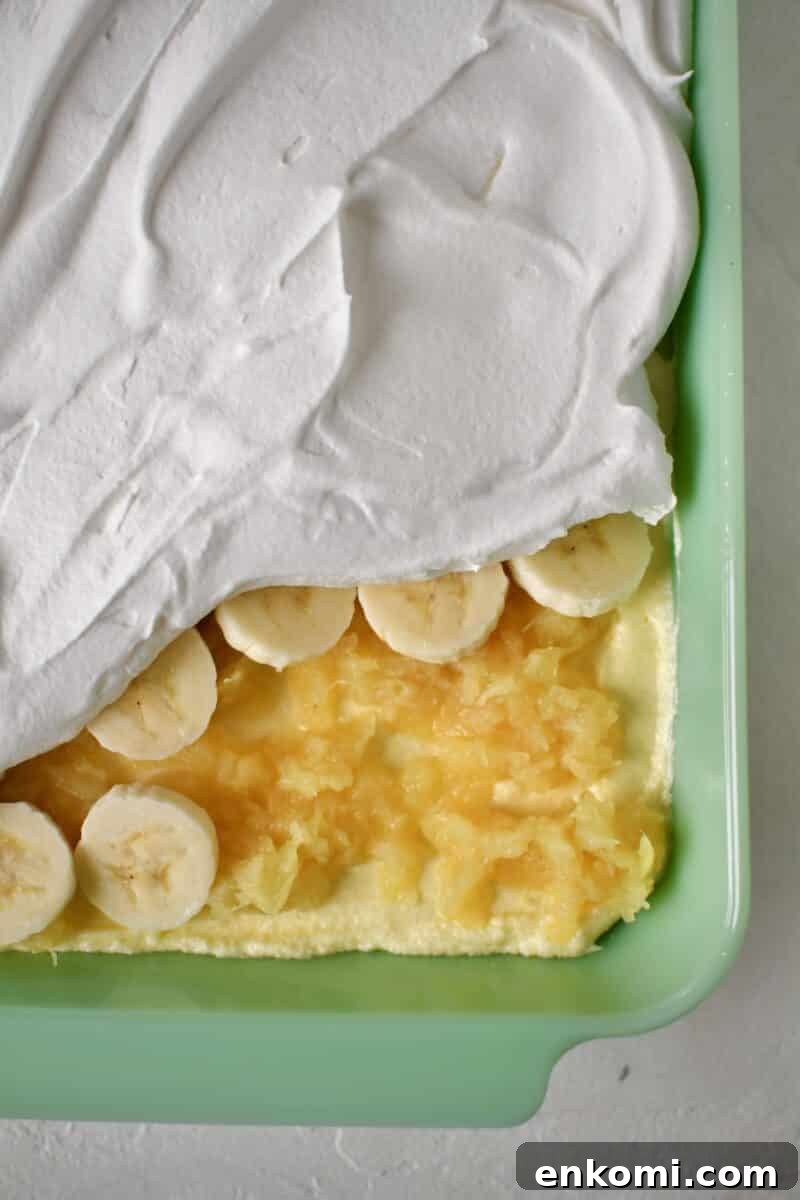 Decadent Banana Split Layer Cake Recipe 9 Finishing the cake by spreading out the crushed pineapple over the filling, adding a layer of bananas and finishing with the whipped topping.