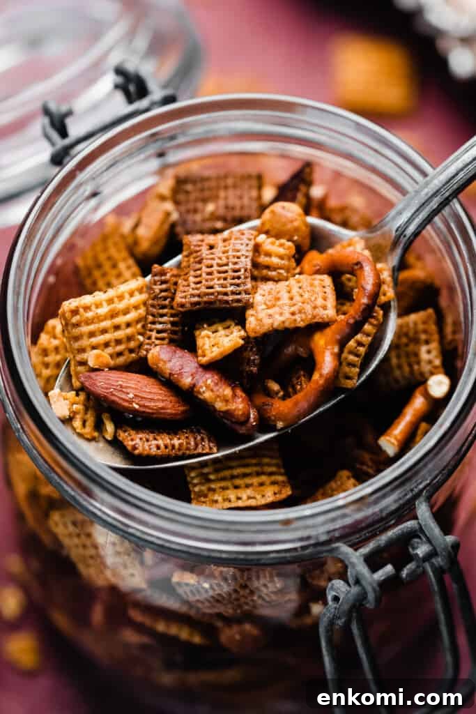 Sweet and Salty Maple Chex Mix Recipe for Snack Lovers 9 A close-up of a jar of the chex mix, with a serving spoon scooping in.