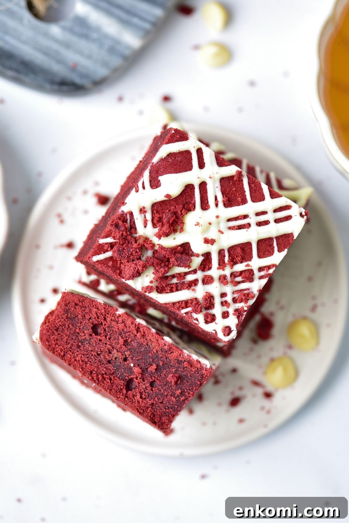 Red brownie cut and served on a small white plate with white chips on the table.
