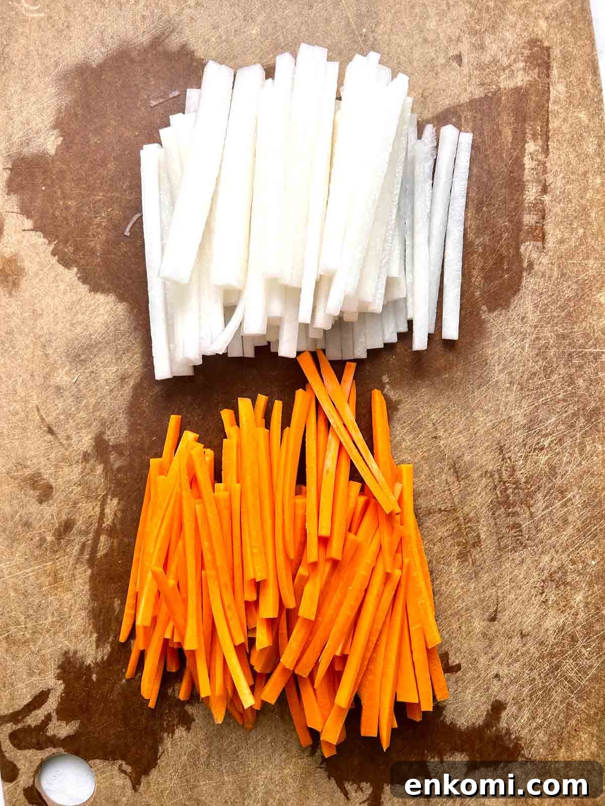 daikon and carrots cut into matchsticks on cutting board.