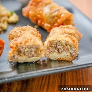 an eggroll filled with ground beef and cheese cut in half on a plate.