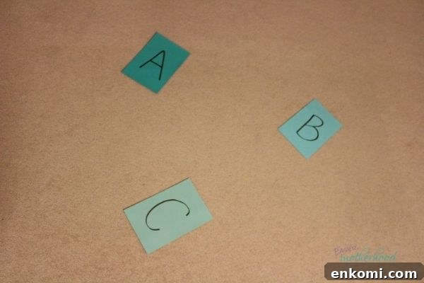 Colored cardstock paper with letters A, B, and C written on them and placed apart for a preschooler to jump to.