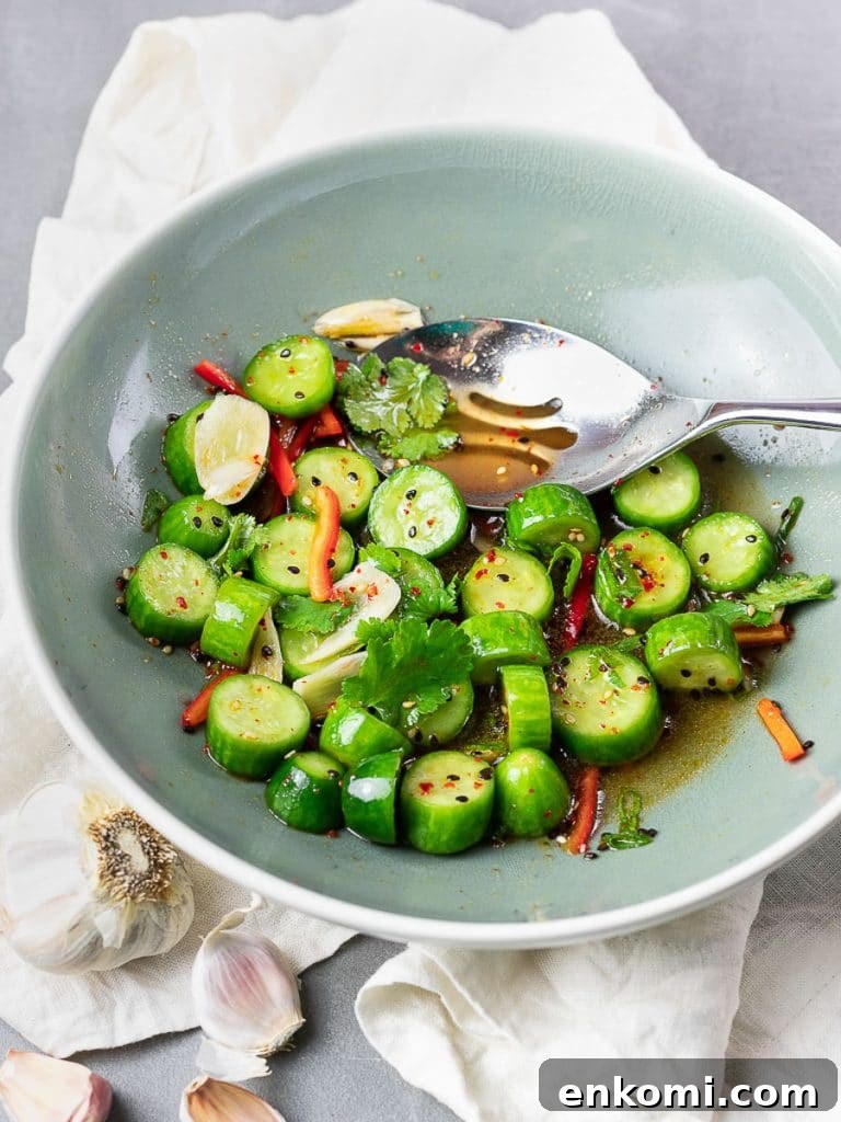 Spicy Asian Cucumber Salad Recipe with Chili-Sesame Dressing 5 Spicy Asian cucumber salad with herbs and red pepper in a blue bowl with a silver spoon