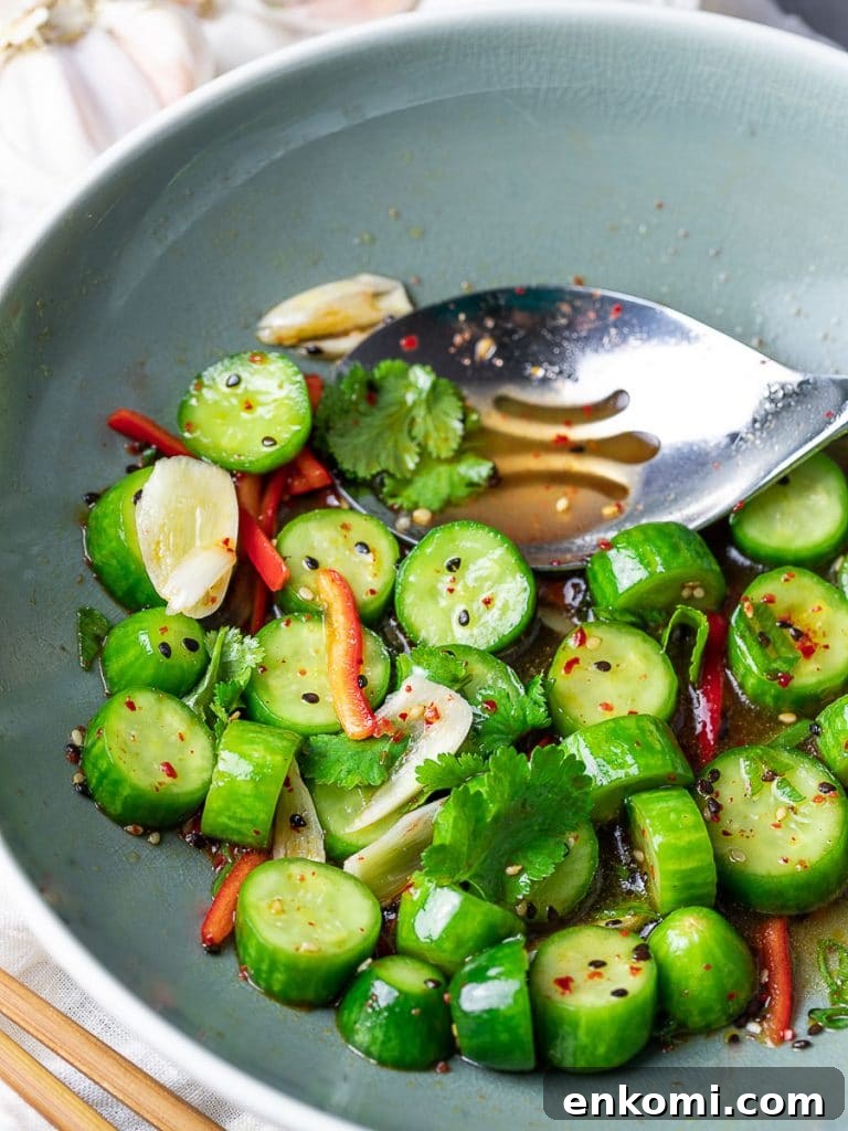 Spicy Asian Cucumber Salad Recipe with Chili-Sesame Dressing 6 Spicy Asian cucumber salad with herbs and red pepper in a blue bowl with a spoon