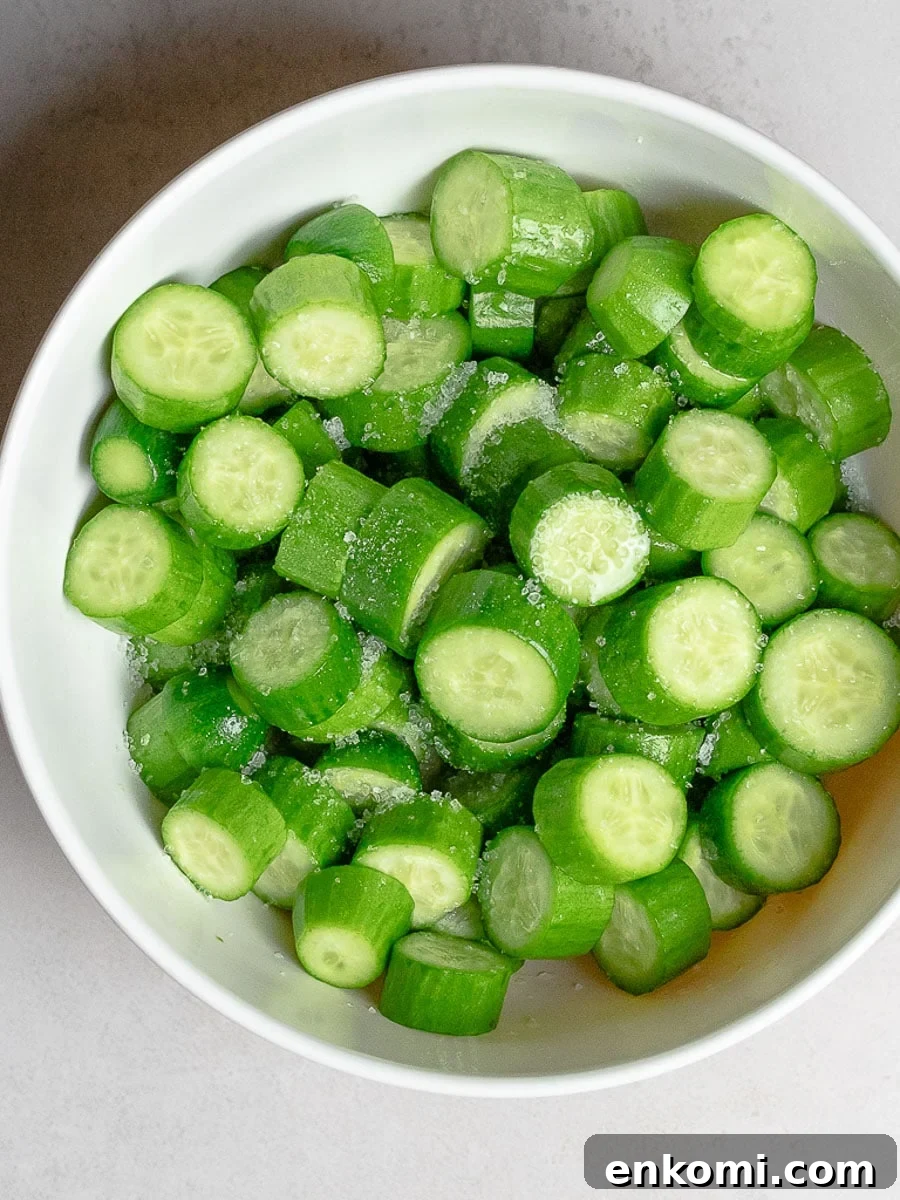 Spicy Asian Cucumber Salad Recipe with Chili-Sesame Dressing 7 chopped persian cucumbers with salt in a bowl