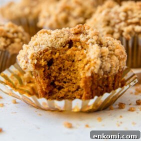 pumpkin muffin with a bite taken out on top of a paper liner