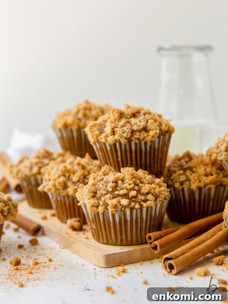 pumpkin muffins with streusel in pile on small wood cutting board next to cinnamon sticks