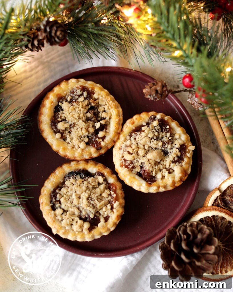 crumble topped mince pies on a purple plate with christmas decorations around