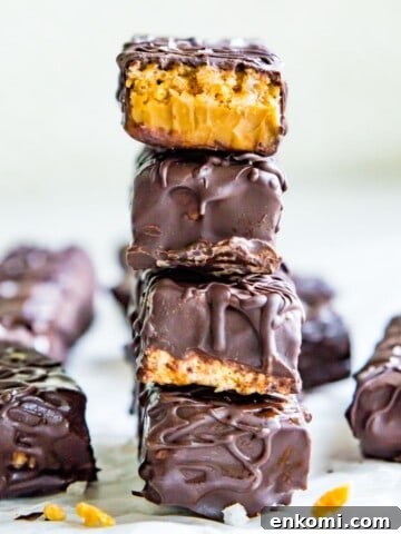 A stack of four chocolate peanut butter cereal bars and the top one has a bite out of it.