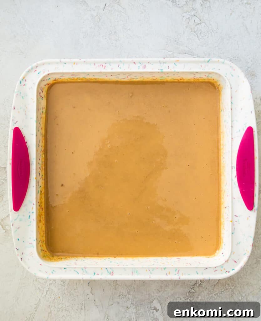 A silicone baking pan with a smooth peanut butter mixture in it.