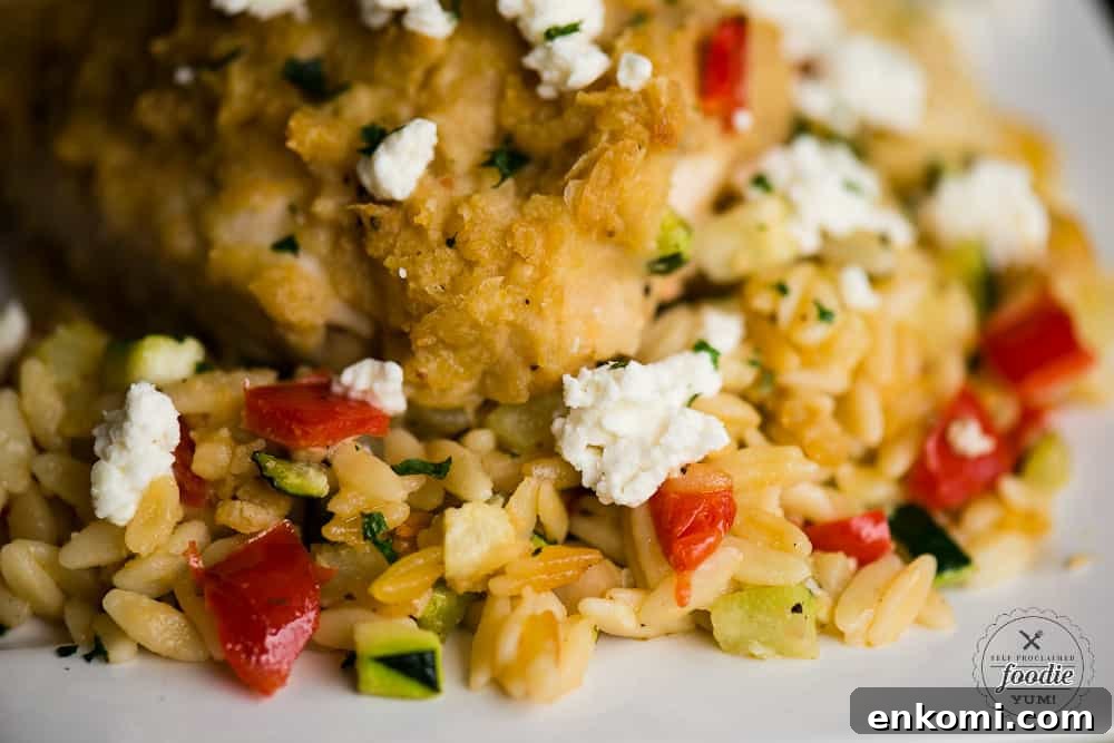 A close up of hummus baked chicken with feta and vegetable orzo