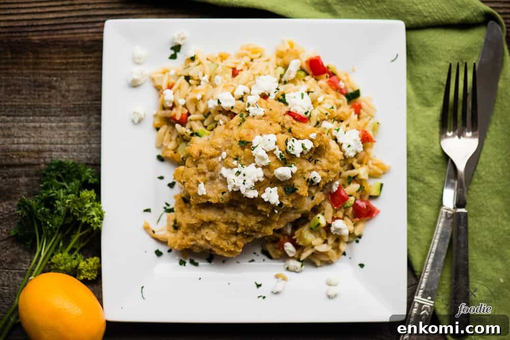 A plate of food with hummus baked chicken with feta and vegetable orzo