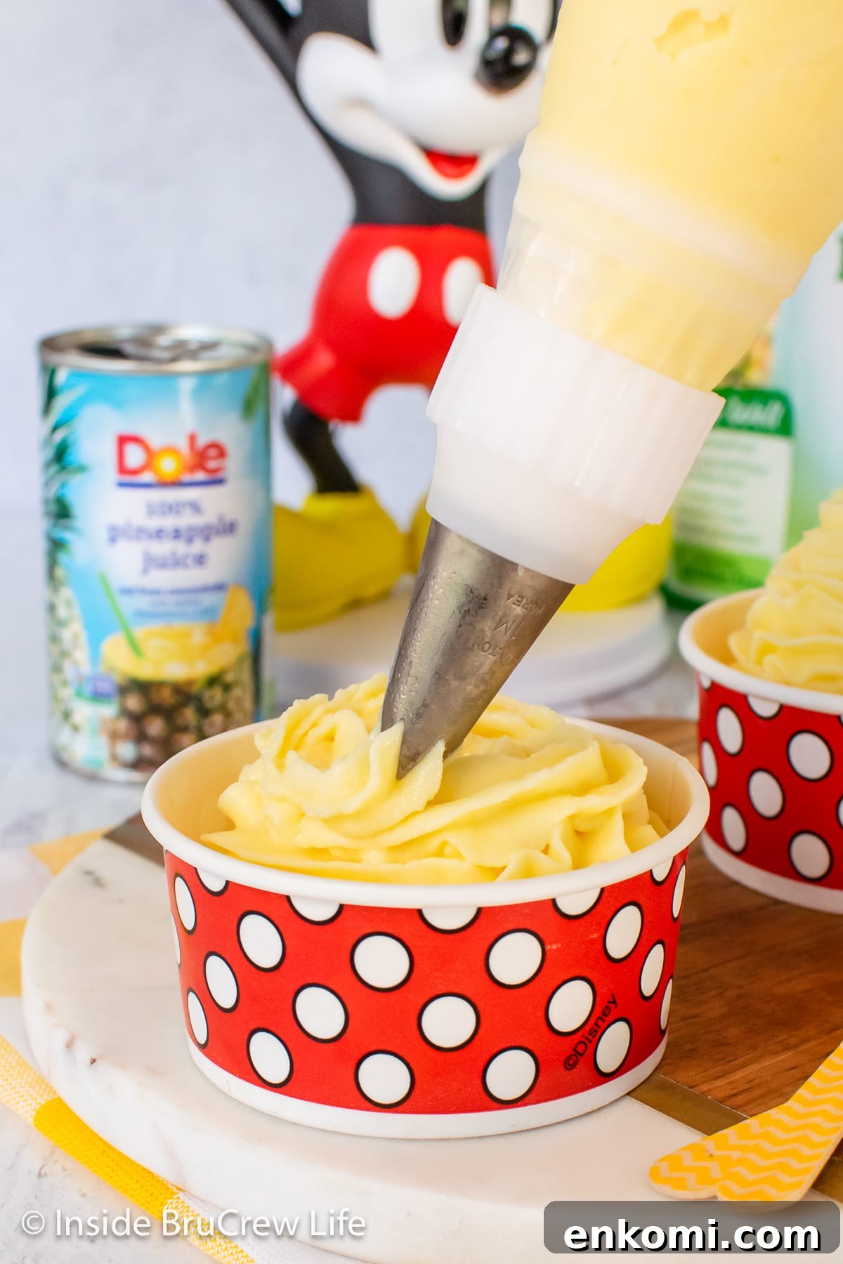 Homemade Pineapple Dole Whip Recipe — Creamy Tropical Soft Serve 5 Frozen pineapple whip being piped into a serving cup.