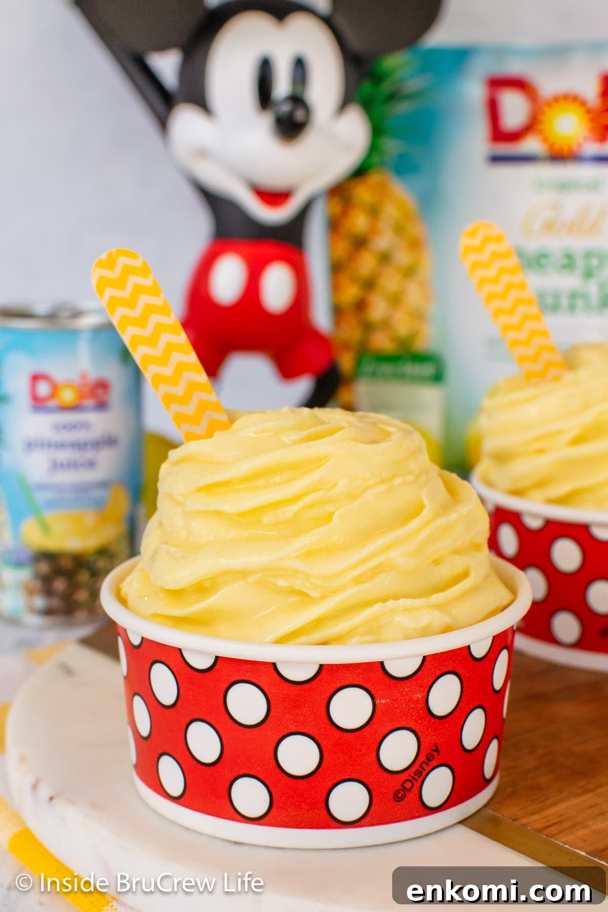 Homemade Pineapple Dole Whip Recipe — Creamy Tropical Soft Serve 7 A red and white cup filled with a swirl of pineapple flavored ice cream.
