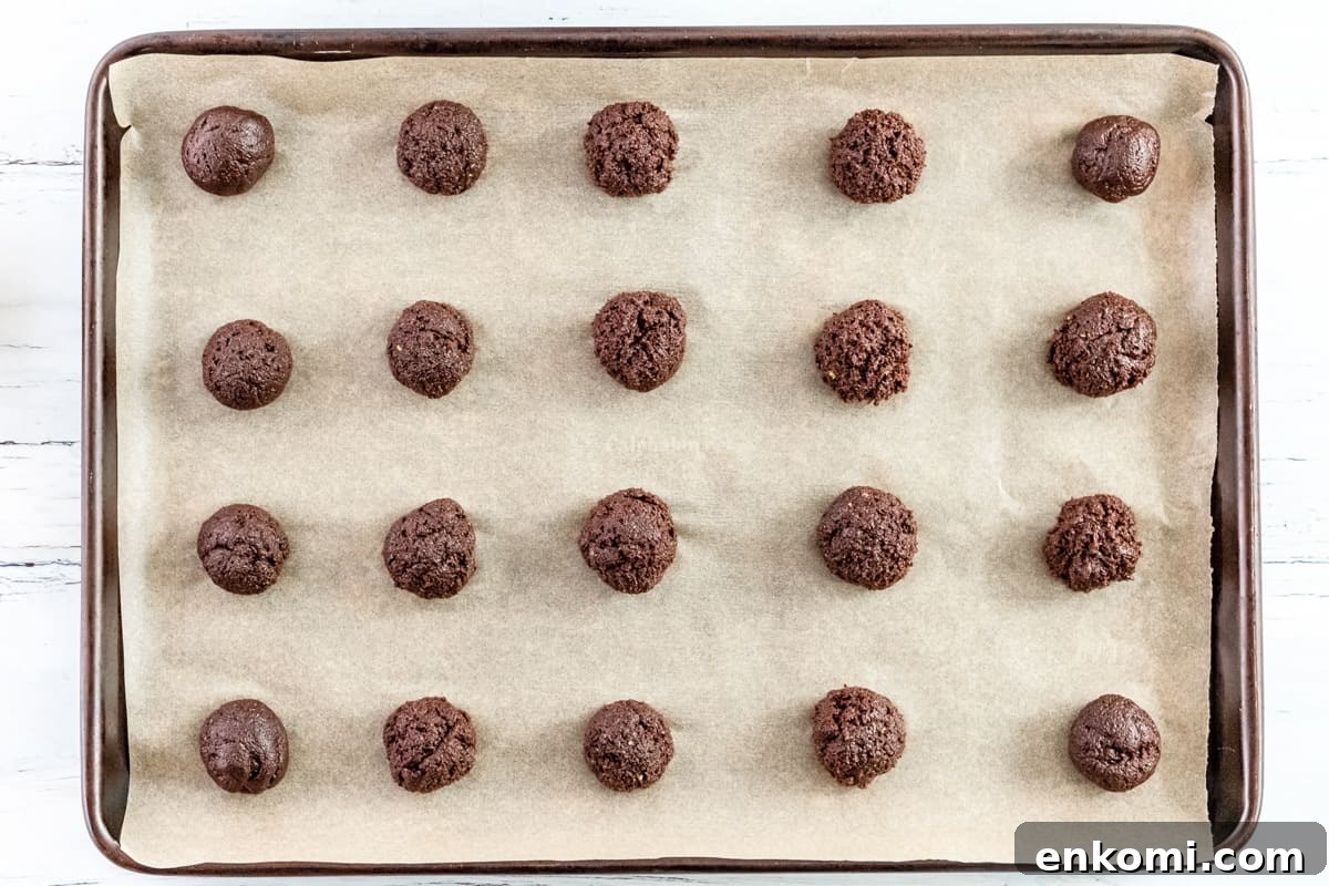 20 thin mint cookie dough balls on a lined baking sheet.
