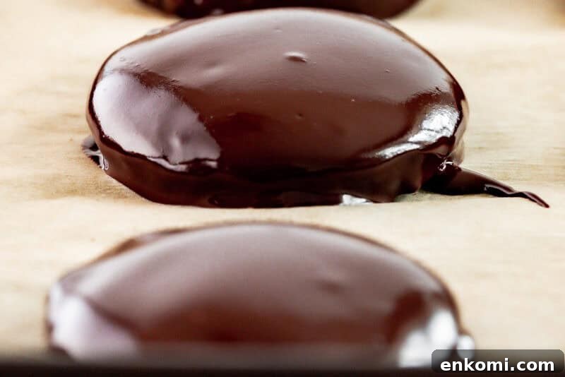 close-up three-quarters view of a row of 3 freshly-dipped thin mints on a baking sheet.