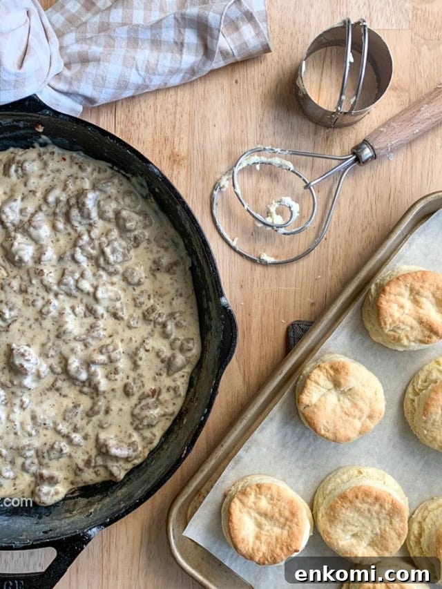 Creamy Sausage Gravy for Biscuits: Homemade Southern Recipe 7 Sausage gravy in a skillet with baked biscuits and tools.