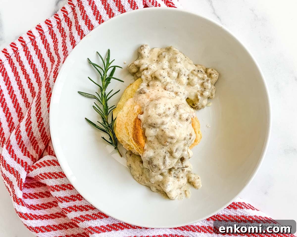 Creamy Sausage Gravy for Biscuits: Homemade Southern Recipe 8 turkey gravy and biscuits in a white plate with red and white napkin ready to serve.